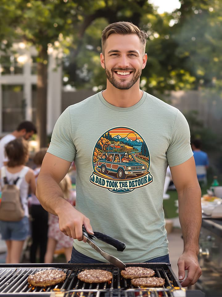 A smiling dad at a backyard grill wearing the Dad Detour Badge t-shirt
